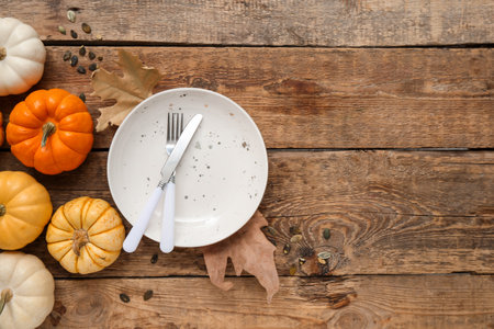 Beautiful table setting with fresh pumpkins, seeds and autumn leaves on wooden backgroundの写真素材