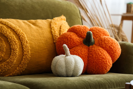 Pillows in shape of pumpkins on green sofa, closeupの写真素材