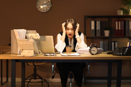 Stressed businesswoman trying to meet deadline in office at nightの写真素材