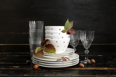 Stack of dishes with autumn decor and acorns on table against black wooden backgroundの写真素材