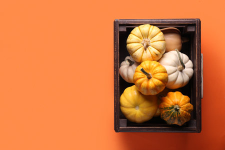 Wooden box with fresh pumpkins on orange backgroundの写真素材
