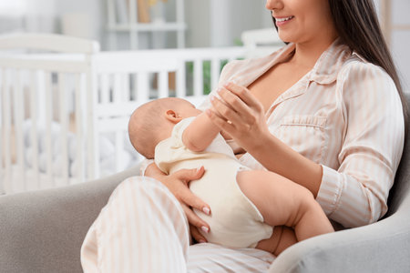 Mother breastfeeding her baby in armchair at home, closeupの写真素材