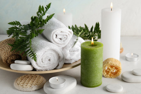 Burning candles, towels, loofah and spa stones on light backgroundの写真素材