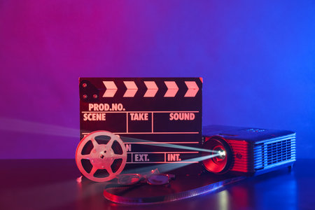 Video projector with movie clapper, glasses and film reel on dark backgroundの写真素材