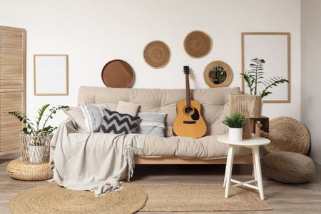 Cozy sofa with guitar, lamp and houseplant on coffee table in interior of living roomの写真素材