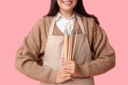 Beautiful female artist with brushes on pink backgroundの写真素材