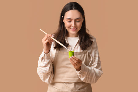 Beautiful female artist with brush and paint on beige backgroundの写真素材