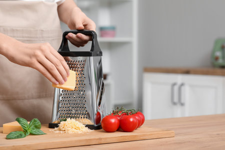 Young woman grating cheese in kitchenの写真素材