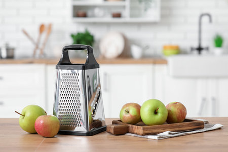 Grater and fresh apples on table in kitchenの写真素材