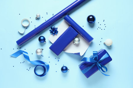 Christmas gift boxes with packing materials and different decorations on blue backgroundの写真素材