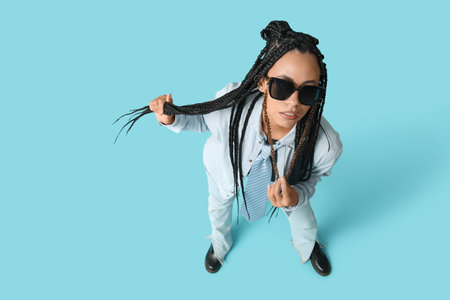 Cool young African-American woman with braids on blue background, top view