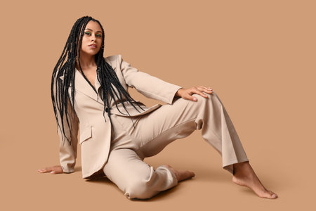 Stylish young African-American woman with braids on beige backgroundの写真素材