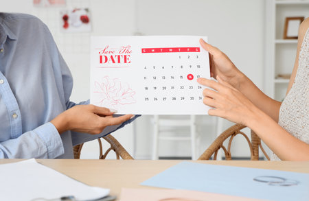 Female wedding planner and client with Save the Date Announcement in office, closeupの写真素材