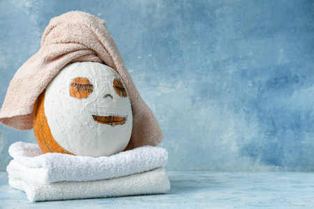 Pumpkin with drawn face, clay mask and towels on blue grunge backgroundの写真素材