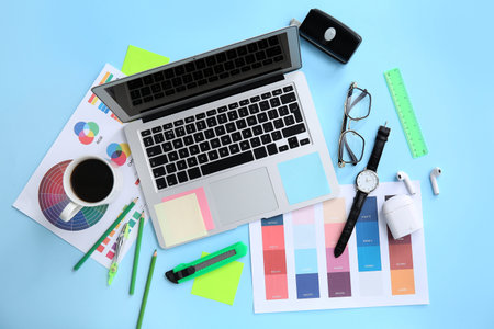 Workplace of graphic designer with laptop, coffee and color charts on blue backgroundの写真素材