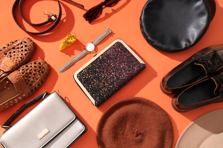 Stylish bags and different accessories on orange background