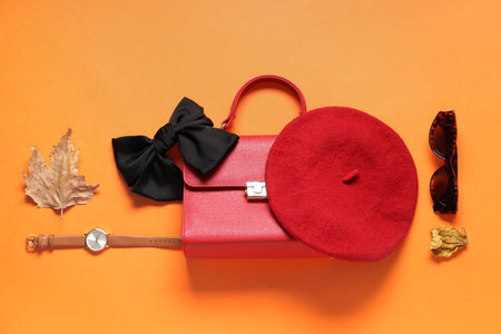 Stylish bag, accessories and dry leaves on orange backgroundの写真素材