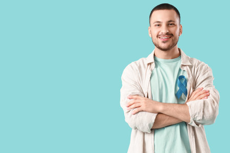 Young man with blue ribbon on color background. Prostate cancer awareness conceptの写真素材