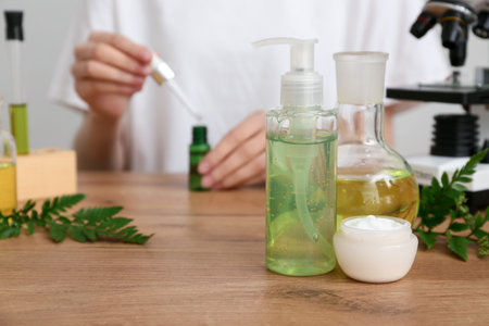 Beautician with microscope, laboratory glassware of samples and ingredients for preparing natural cosmetics, closeupの写真素材