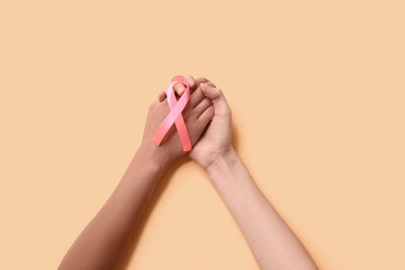 Female hands and pink ribbon on color background, closeup. Breast cancer awareness conceptの写真素材