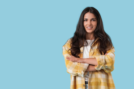 Portrait of pretty young woman with crossed arms on blue backgroundの写真素材