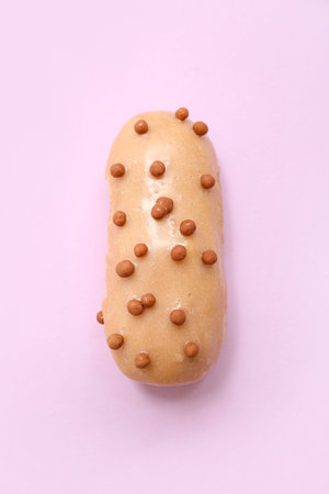 Sweet glazed eclair on pink background