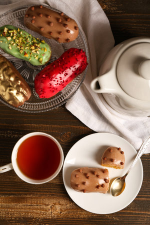 Sweet eclairs and tea on wooden background