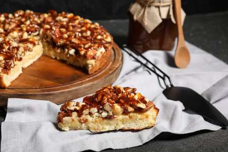 Wooden board of cut sweet tart with different nuts and caramel on black backgroundの写真素材