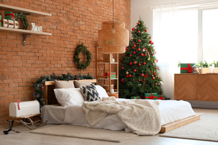 Interior of bedroom with Christmas tree, gifts and decor near orange brick wallの写真素材
