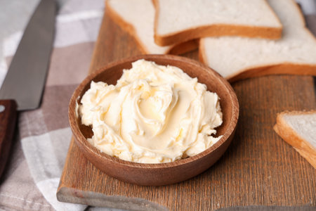 Wooden board with bowl of fresh butter and toasts, closeupの写真素材