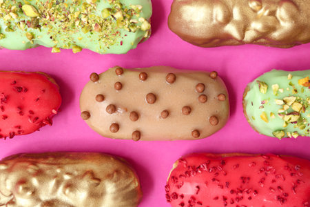 Composition with tasty glazed eclairs on pink background