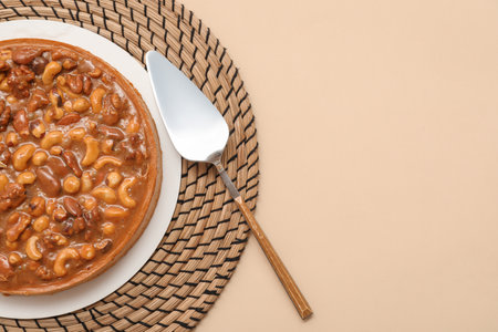 Plate of sweet tart with different nuts and caramel on beige backgroundの写真素材