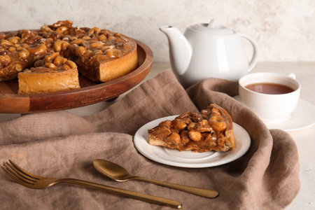 Wooden board and plate of cut sweet tart with different nuts and caramel on white backgroundの写真素材