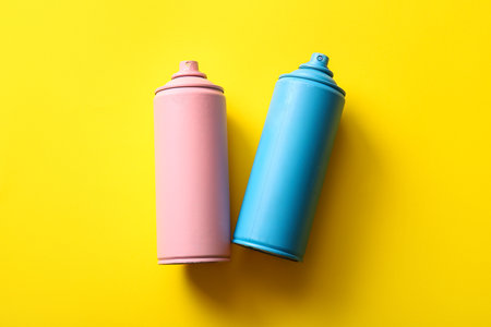 Spray paint cans on yellow backgroundの写真素材