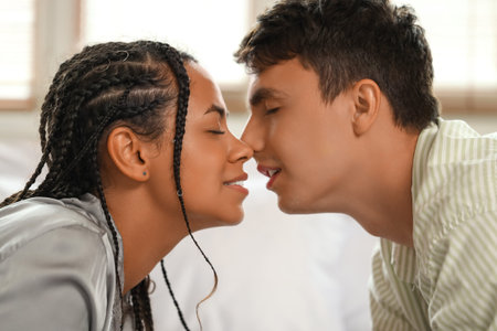 Young couple kissing in bedroom, closeup