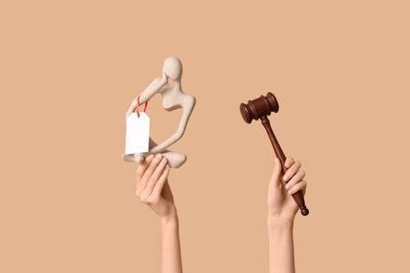 Woman holding auction gavel and antique statuette on beige backgroundの写真素材