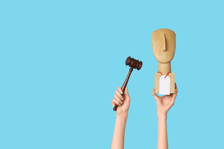 Woman holding auction gavel and antique item on blue background