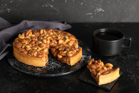 Boards of cut sweet tart with different nuts and caramel on black backgroundの写真素材