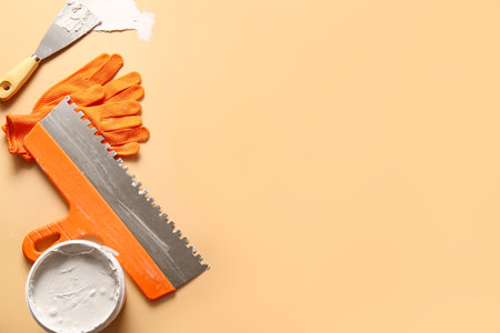 Knives, gloves and can of putty on beige backgroundの写真素材