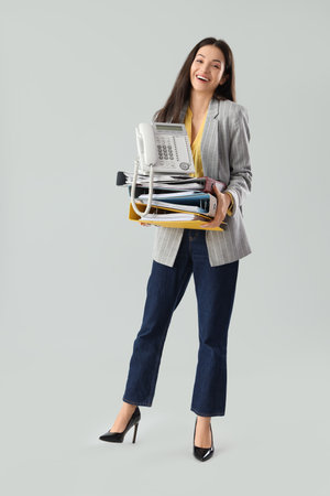 Beautiful businesswoman with folders and telephone on light backgroundの写真素材