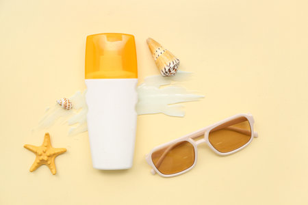 Composition with bottle of sunscreen cream, seashells and sunglasses on beige backgroundの写真素材
