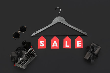 Composition with word SALE, hanger, accessories and gift box on dark backgroundの写真素材