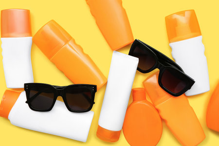 Composition with bottles of sunscreen cream and sunglasses on yellow background, closeupの写真素材