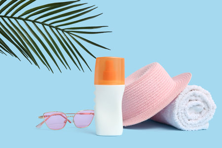 Sunglasses, hat, bottle of sunscreen cream and towel on blue backgroundの写真素材
