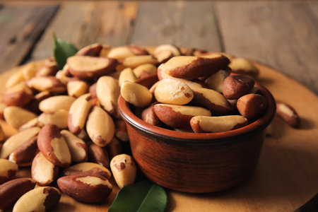 Bowl and board with tasty Brazil nuts on wooden background, closeupの写真素材