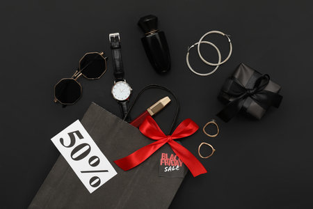 Composition with shopping bag, stylish accessories and gift box on dark background. Black Friday saleの写真素材