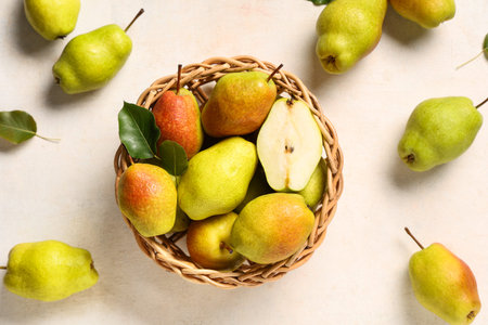 Wicker bowl with sweet ripe pears on white background