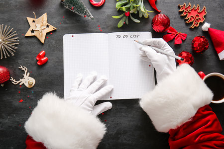 Santa Claus writing to-do list with Christmas decor on dark backgroundの写真素材