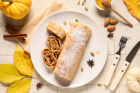 Plate with tasty pumpkin strudel, seeds, star anise and cinnamon on white tile backgroundの写真素材