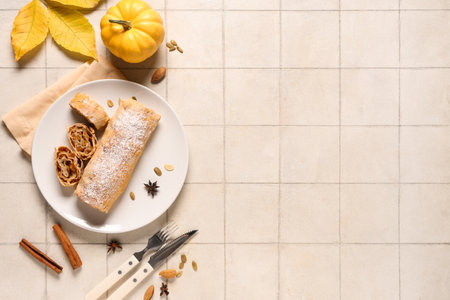 Plate with tasty pumpkin strudel, seeds, star anise and cinnamon on white tile backgroundの写真素材